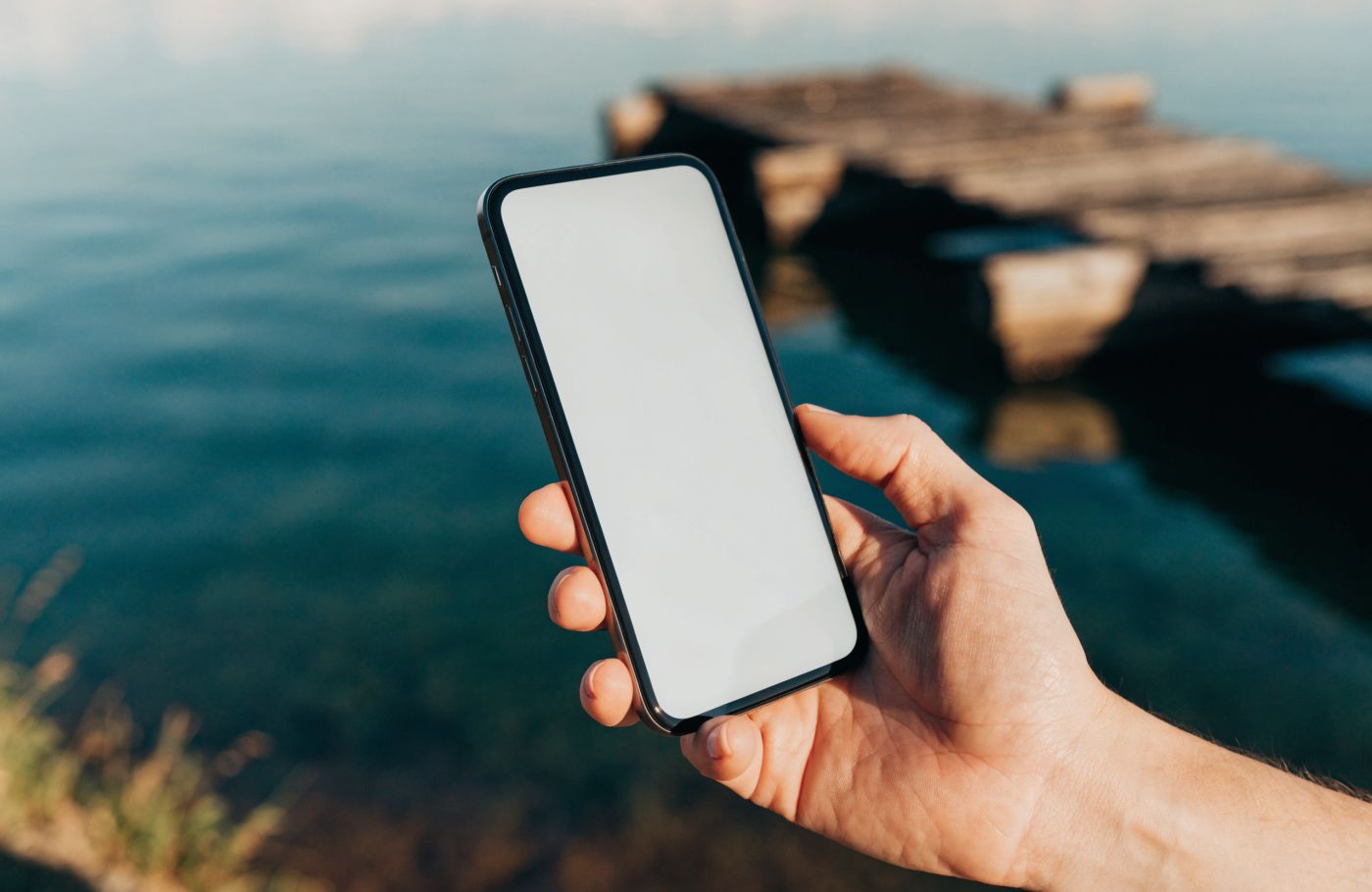 Gast hält das Handy mit der Karte am Seeufer